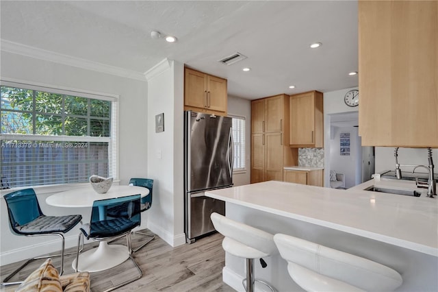 kitchen with sink, light hardwood / wood-style flooring, decorative backsplash, stainless steel fridge, and kitchen peninsula