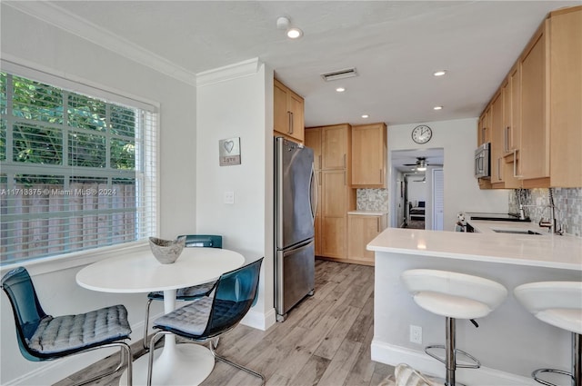 kitchen with kitchen peninsula, decorative backsplash, stainless steel appliances, light brown cabinets, and light hardwood / wood-style flooring