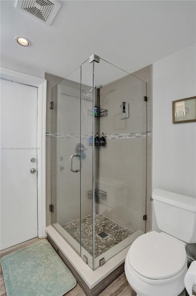 bathroom with a shower with shower door and toilet