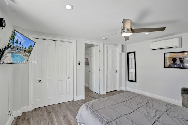 bedroom with ceiling fan, a wall mounted air conditioner, and light wood-type flooring