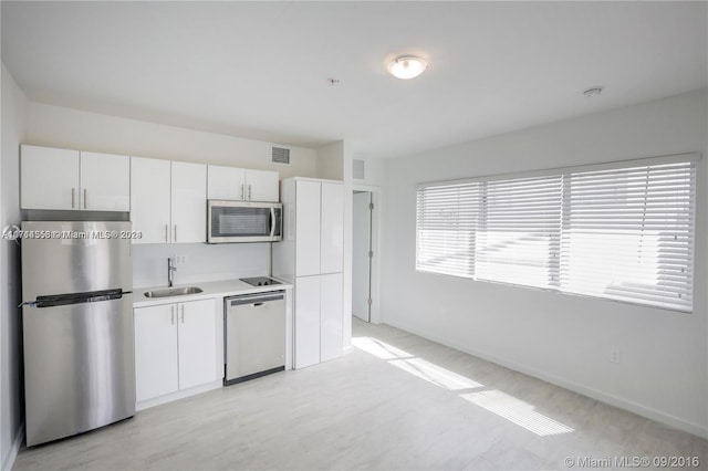 kitchen with a wealth of natural light, white cabinetry, sink, and appliances with stainless steel finishes