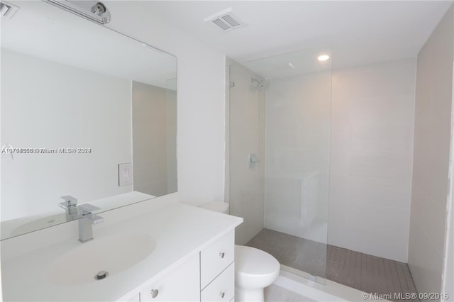 bathroom featuring tiled shower, vanity, and toilet