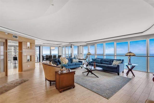 living room featuring floor to ceiling windows, a water view, and light hardwood / wood-style floors