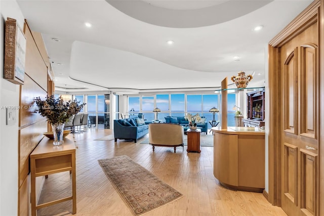 living room with plenty of natural light, expansive windows, a water view, and light hardwood / wood-style floors