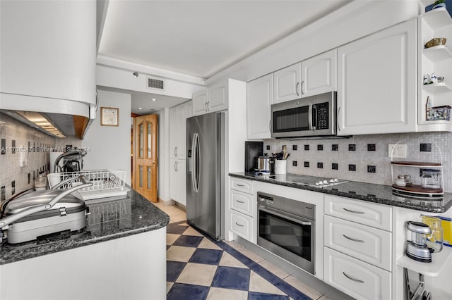 kitchen featuring backsplash, dark stone countertops, white cabinetry, and appliances with stainless steel finishes