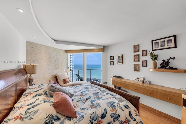 bedroom featuring access to outside, a water view, and light hardwood / wood-style flooring