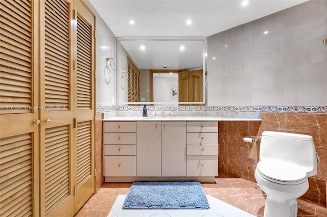 bathroom with tile patterned floors, vanity, toilet, and tile walls