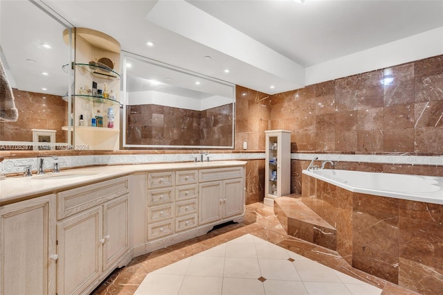 bathroom featuring tile patterned floors, vanity, tile walls, and tiled bath