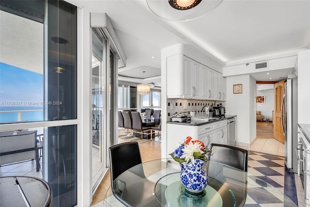 kitchen with white cabinets, backsplash, dark stone countertops, and stainless steel appliances