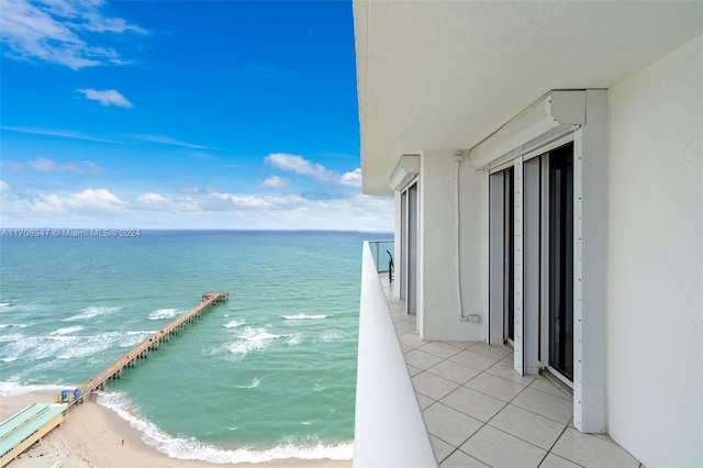 balcony with a water view and a view of the beach