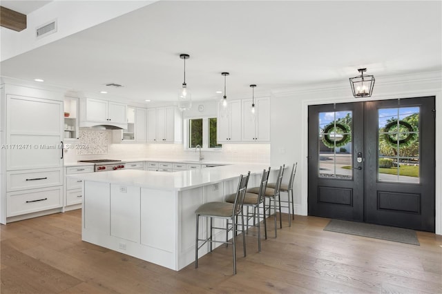 kitchen with decorative light fixtures, white cabinetry, a breakfast bar, and french doors