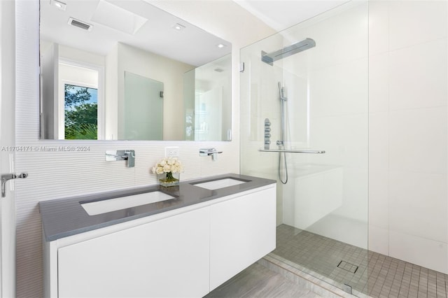 bathroom with tiled shower, vanity, tile patterned floors, and tile walls