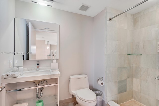 bathroom featuring toilet, a tile shower, and vanity