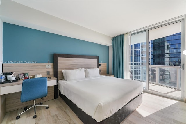 bedroom with a wall of windows, access to outside, and light hardwood / wood-style flooring