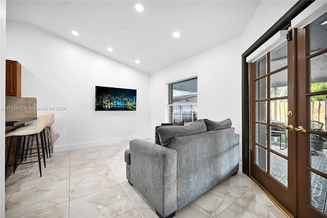 living room with a healthy amount of sunlight, lofted ceiling, and french doors