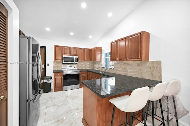 kitchen featuring sink, kitchen peninsula, vaulted ceiling, a breakfast bar area, and appliances with stainless steel finishes