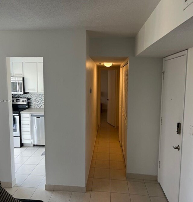 corridor with light tile patterned floors and a textured ceiling