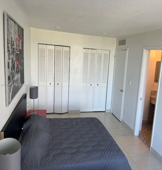 tiled bedroom with multiple closets and a textured ceiling