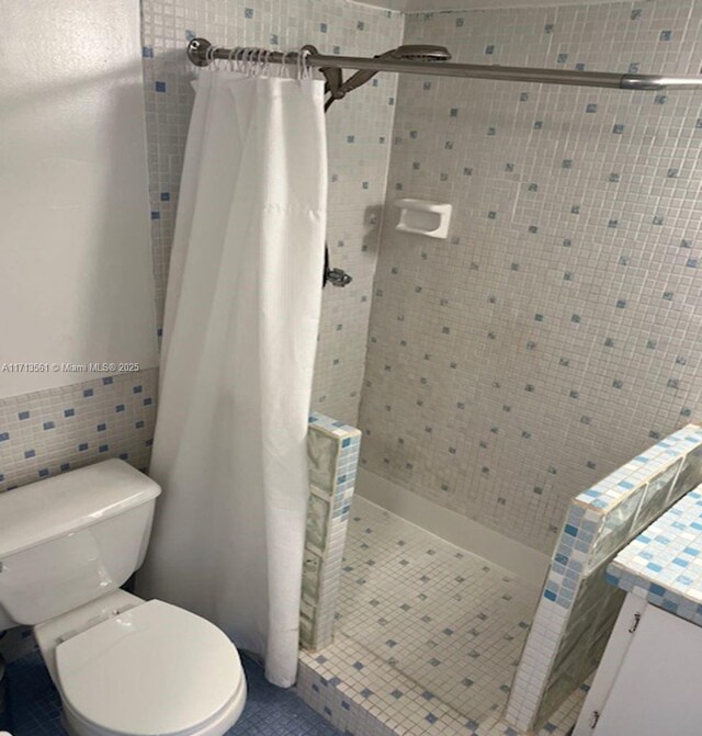 bathroom with toilet, tile walls, and a shower with shower curtain