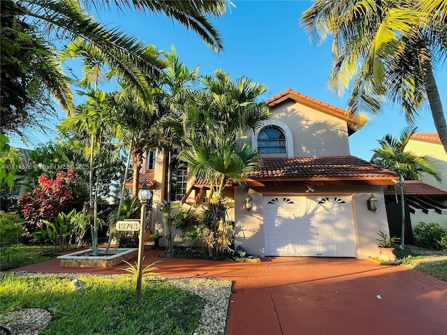 mediterranean / spanish house featuring a garage, concrete driveway, a tile roof, and stucco siding