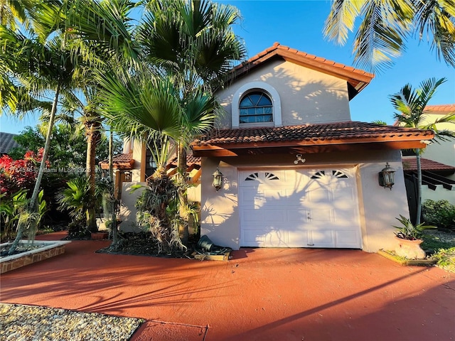 view of front of home with a garage, a tile roof, driveway, and stucco siding