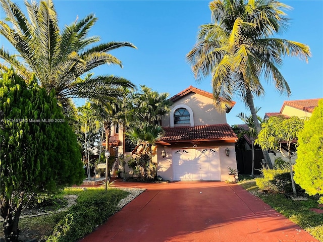 mediterranean / spanish house featuring a tile roof, driveway, an attached garage, and stucco siding