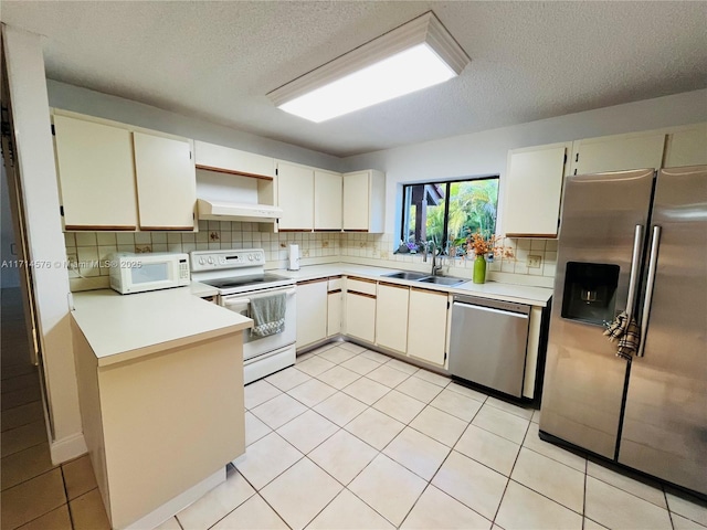 kitchen with stainless steel appliances, a sink, light countertops, and decorative backsplash