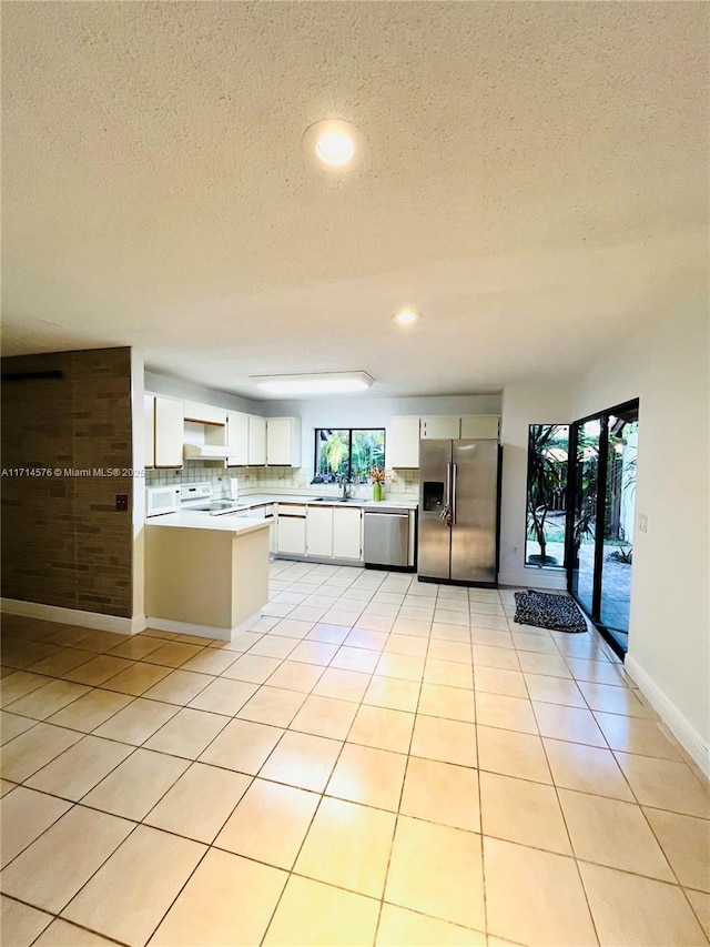 kitchen featuring light tile patterned floors, white cabinets, appliances with stainless steel finishes, light countertops, and a sink