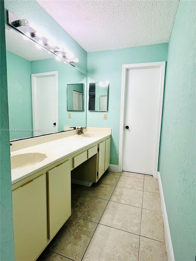 bathroom featuring a textured ceiling, double vanity, tile patterned flooring, and a sink