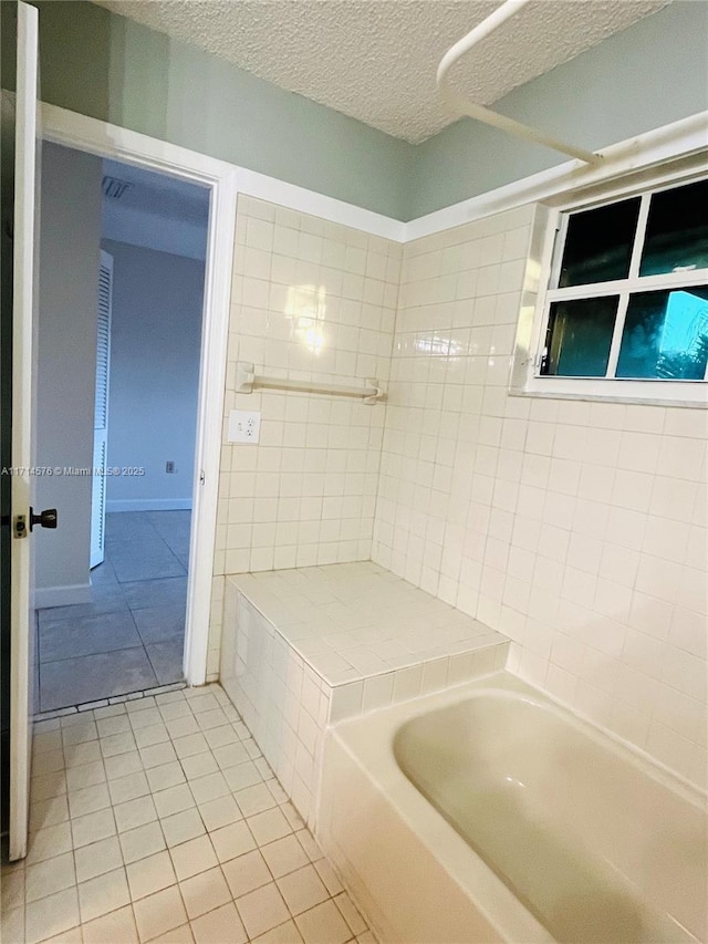 bathroom with a washtub, walk in shower, a textured ceiling, and tile patterned floors