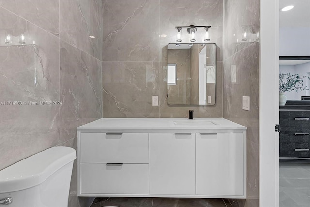 bathroom with vanity, tile walls, and toilet