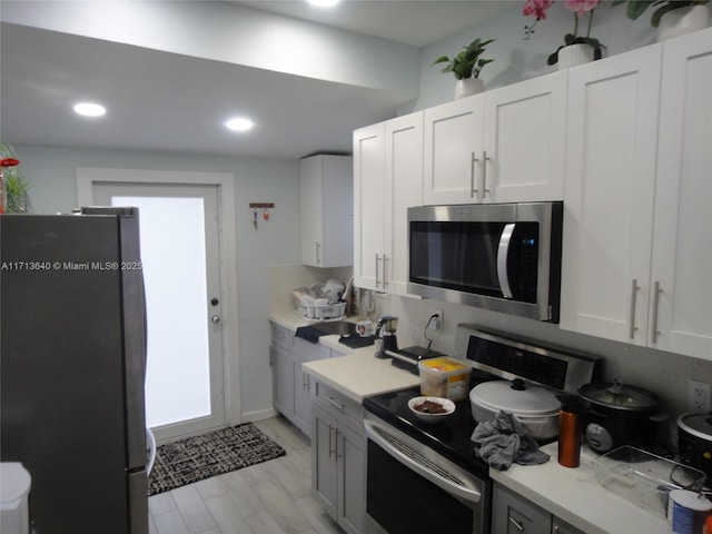 kitchen featuring gray cabinets, white cabinetry, light hardwood / wood-style flooring, and stainless steel appliances