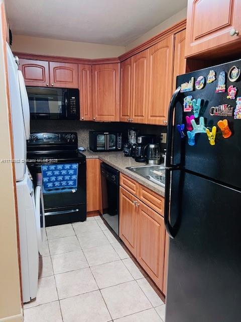 kitchen with sink, light tile patterned flooring, and black appliances