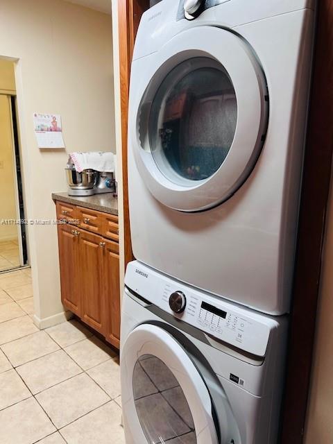 washroom with stacked washer / drying machine and light tile patterned floors