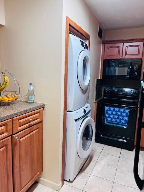 washroom featuring light tile patterned flooring and stacked washing maching and dryer