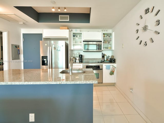 kitchen with light stone countertops, sink, light tile patterned floors, white cabinets, and appliances with stainless steel finishes