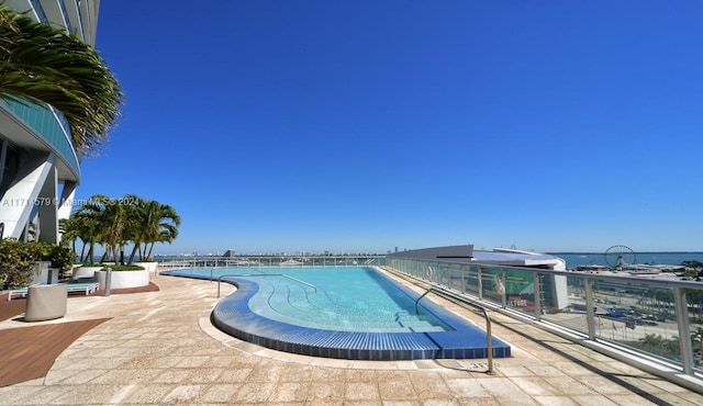 view of pool with a water view and a patio