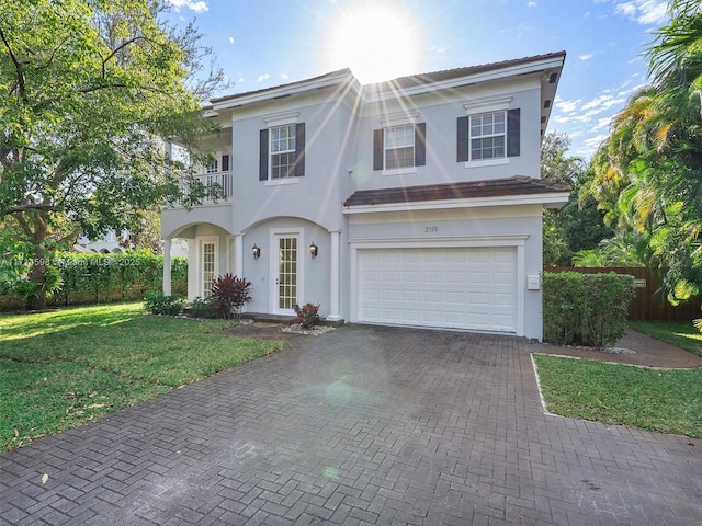 view of front of property featuring a garage, a balcony, and a front yard