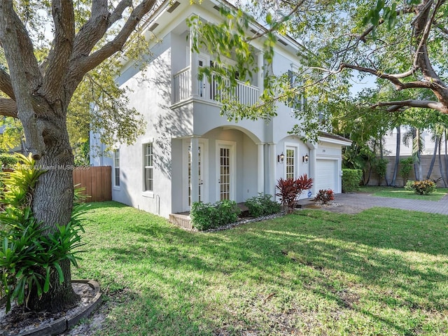 view of front of property with a garage, a balcony, and a front lawn