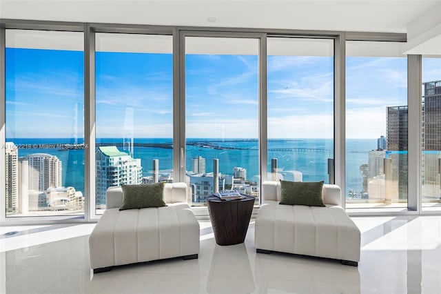 living room featuring floor to ceiling windows, a water view, and light tile patterned floors