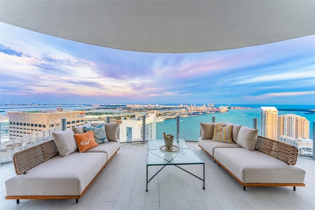 balcony at dusk featuring outdoor lounge area and a water view