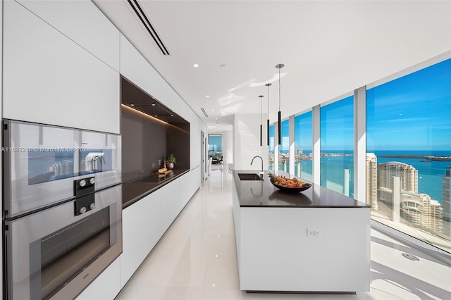 kitchen featuring sink, pendant lighting, a water view, white cabinetry, and oven