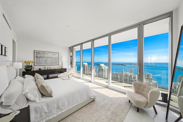 bedroom featuring floor to ceiling windows, a water view, and access to outside