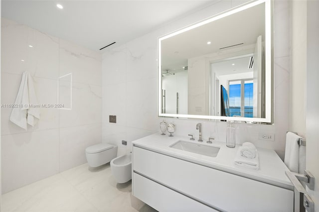 bathroom with vanity, a bidet, toilet, and tile walls