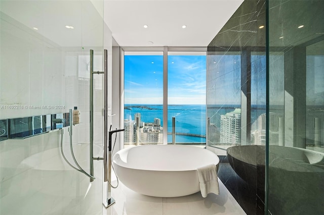 bathroom with tile patterned flooring, expansive windows, a water view, and a bath