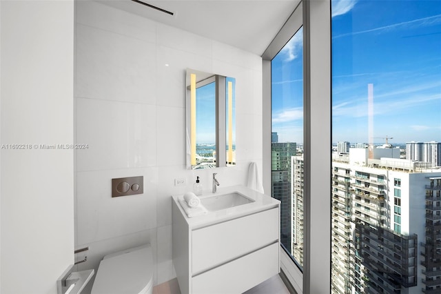 bathroom with vanity, tile walls, and toilet