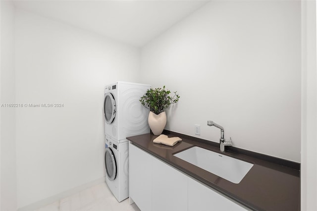 clothes washing area with sink, light tile patterned floors, and stacked washer and clothes dryer