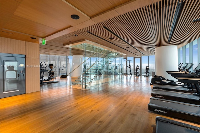 gym featuring a wall of windows, wood-type flooring, and wooden ceiling