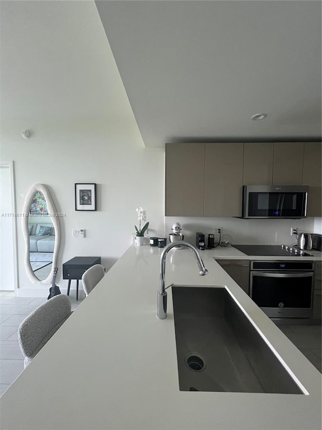 kitchen featuring gray cabinetry, kitchen peninsula, light tile patterned floors, and stainless steel appliances