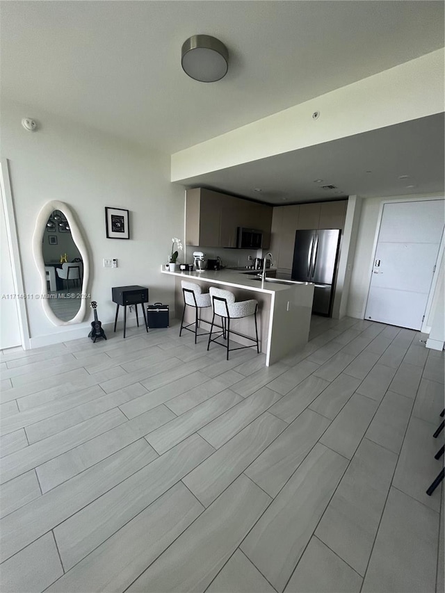 kitchen featuring kitchen peninsula, a kitchen breakfast bar, stainless steel appliances, and sink